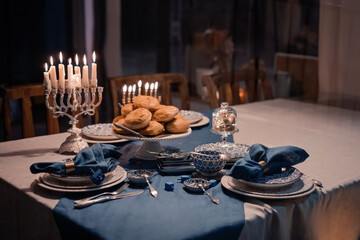 Wall Mural - Food for Hanukkah celebration: Menorah Candles on wooden table, sufganiyot cake and table setting, jewish symbol centerpieces, white and blue. holiday Israel hebrew traditional family celebration