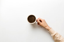 Minimalistic Style Woman Hand Holding A Cup Of Coffee On Colored Background. Flat Lay, Top View Cappuccino Cup. Empty Place For Text, Copy Space. Coffee Addiction. Top View, Flat Lay