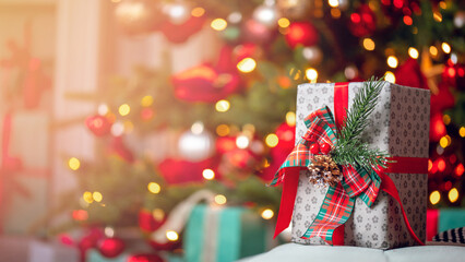 Closeup gift box with bowknot on blurred background red decorated christmas tree pine bokeh sun light banner