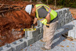 Contractor during installation of new large block retaining wall in construction site