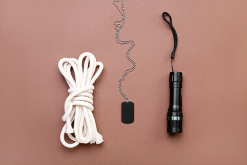 Wall Mural - Military tag, flashlight and rope on color background