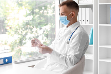 Wall Mural - Male doctor in medical mask with syringe at hospital