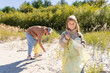 © Julija - Earth day. Cleanup garbage on the ocean coast. A volunteers Father and daughter with polyethielene bag picking up a plastic bottle on the beach.