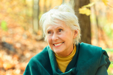 Wall Mural - Happy elderly senior woman in an autumn park.