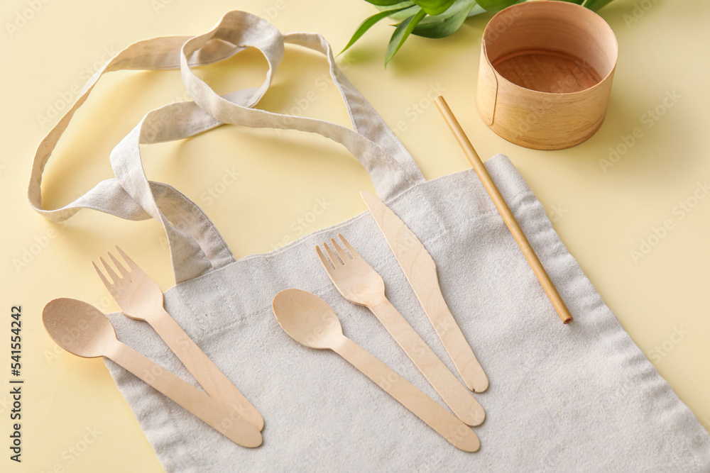 Fabric tote bag, Eco tableware and plant branch on yellow background