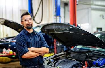 Wall Mural - Handsome mechanic job in uniform working on car