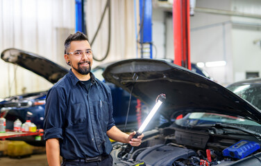 Wall Mural - Handsome mechanic job in uniform working on car