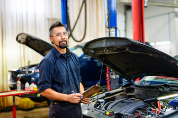 Wall Mural - Handsome mechanic job in uniform working on car