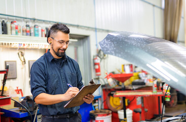 Wall Mural - Handsome mechanic job in uniform working on car