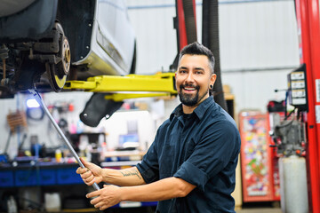 Wall Mural - Handsome mechanic job in uniform working on car