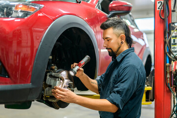 Wall Mural - Handsome mechanic job in uniform working on car