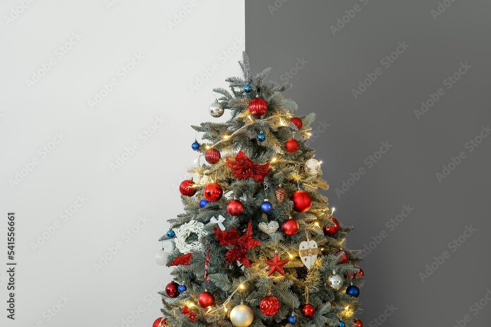 Christmas tree with glowing lights near black and white wall