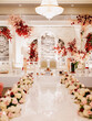Front view of beautifully decorated room for a wedding celebration. Wedding altar with road among floral composition and chairs for bride and groom