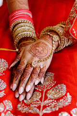 Wall Mural - Close-up hands of Indian woman with gold kundan jewelry on her hands, dressed in red ceremonial dress