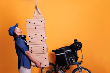 Senior takeaway delivery standing with giving food order and holding pizza boxes, pizzeria service. Restaurant courier transporting takeout food with bike on yellow background. Takeout concept