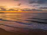 Fototapeta Zachód słońca - Peaceful sunrise over the ocean with small waves and clouds