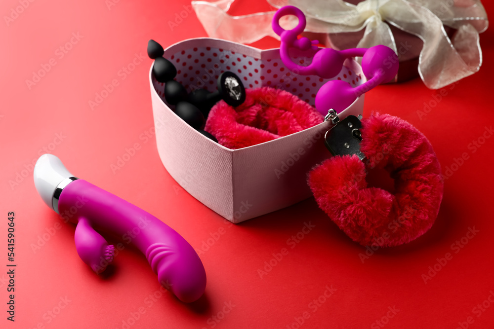 Gift box with different sex toys on red background Stock Photo | Adobe Stock