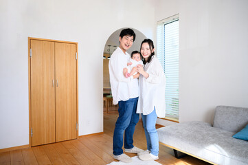 Wall Mural - Portrait of Asian family looking at camera in living room Wide angle full body