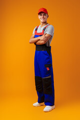 Wall Mural - Full length shot of a young male worker in uniform on yellow background