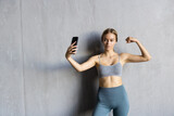Fototapeta Łazienka - Young smiling sporty athletic fitness trainer instructor woman doing exercises do selfie shot on mobile phone sit on mat floor at home