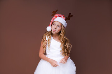 Happy funny child girl in red christmas deer costume smiling looking at camera. Caucasian teenager waiting for christmas and new year