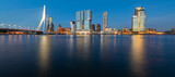 Fototapeta  - Rotterdam Netherlands wide angle nighttime panorama with skyline, modern buildings and iconic bridge. Evening sky reflection in River Maas harbour at blue hour with colorful illumination