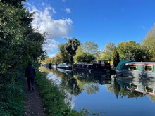 Rear View Of A Man Walking Along A Towpath And Narrowboats Moored Along Grand Union Canal, Bourne End, Hertfordshire, England, UK