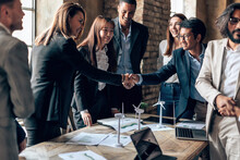 Diverse Multiethnic Businesspeople Shaking Hands At Meeting Table - Company Agreement - Project Approved