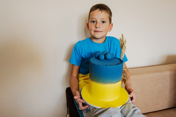 Ukrainian boy kid celebrating birthday holding big cake with flag of Ukraine.