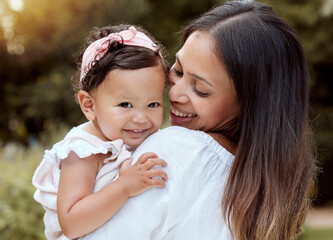 Happy mother with girl baby hug in a park with summer love, smile and care or growth development wellness. Happy latino mom with kid in portrait together nature outdoor for mothers day with happiness