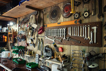 Various Tools Hang On A Wooden Wall In A Workshop