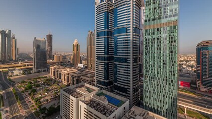 Wall Mural - Aerial morning view of Dubai International Financial District with many skyscrapers timelapse. Traffic on a road near multi storey parking with long shadows during sunrise. Dubai, UAE.