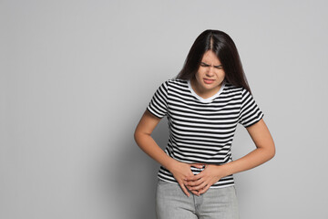 Wall Mural - Young woman suffering from menstrual pain on grey background, space for text