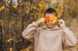 © Lyubov - Teenager boy hiding his eyes behind maple leaves. Child holding yellow autumn leaves in his hands. Teen having fun on walking in autumn park. Selective focus
