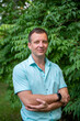 © Beliakina Ekaterina - Portrait of a 30-40-year-old man in a light green shirt against a green tree in summer