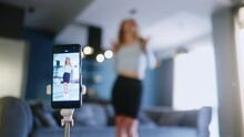 Blonde girl recording video of trendy dance challenge for likes and followers on social media platform. Woman funny dancing, filming her performance for stories on smartphone camera at home studio.