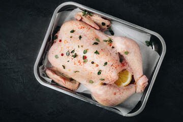 Wall Mural - Chicken. Whole fresh raw free range chicken with spices on dark background, ready to cook, top view