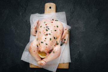 Wall Mural - Chicken. Whole fresh raw free range chicken with spices on dark background, ready to cook, top view