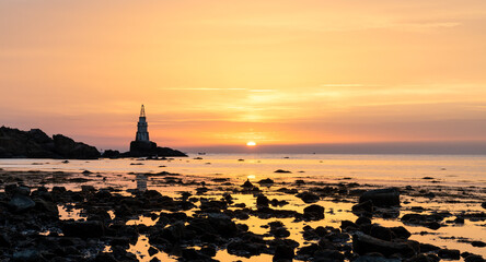 Wall Mural - sunrise on the Bulgarian Black Sea coast in Athopol with the harbor lighthouse and rocky shore