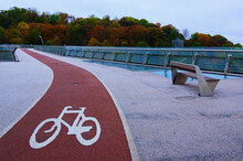 Scenic Autumn Landscape View Of Winding Red Color Bike Lane With White Bicycle Sign On The New Pedestrian Bridge In Kyiv, Ukraine. Beautiful Autumn Colored Trees In The Background
