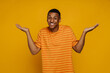© Drobot Dean - Smiling afro man shrugging shoulders and spreads hands sideways while standing isolated