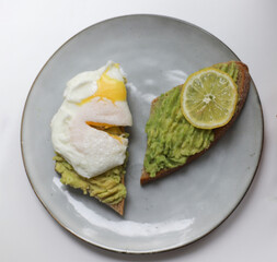 on a gray kitchen round plate
 there are two sandwiches on black bread with ingredients such as avocado pate, lemon and egg. for banners, labels, shop signs, books with recipes