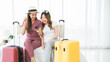 Two happy Asian women booked a hotel room on a smart phone and pay with a credit card while sitting together on the bed with their luggage. Planning on holiday vacation trip.
