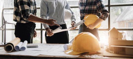 Civil engineer teams meeting working together wear worker helmets hardhat on construction site in modern city. Foreman industry project manager engineer teamwork. Asian industry professional team