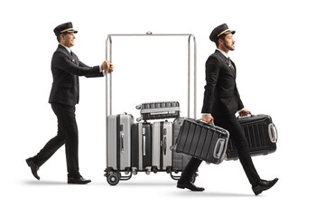 Wall Mural - Bellboy carrying suitcases and other pushing suitcases on a hotel luggage cart