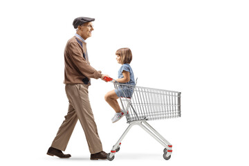 Wall Mural - Full length profile shot of an elderly man walking with a child in a shopping cart