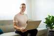 © Louis-Paul Photo - technology, people and online shopping concept - happy smiling man with laptop computer at home