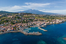 Aerial View Of Aci Trezza, A Small Town Along The Coast With Etna Volcano In Background, Sicily, Italy.