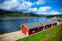 the harsh landscape of the norwegian fjords on the Lofoten islands, small houses by the sea with huge mountains above them