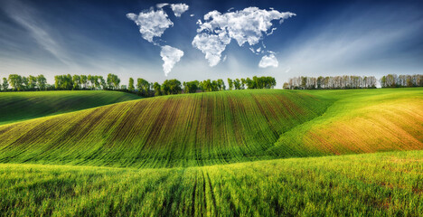 clouds in the form of a world map over a green field. Travel and landscape concept. hilly field